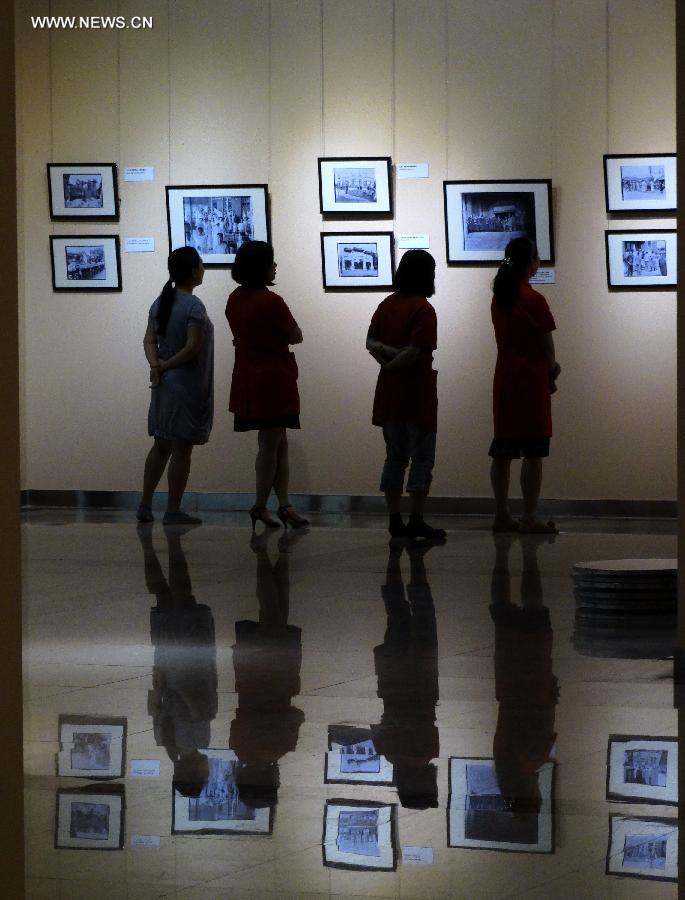 Citizens watch pictures during a photo exhibition displaying the works of Sidney D. Gamble in Beijing, capital of China, June 18, 2013. The exhibition displayed more than 100 photos taken by Gamble depicting the life of Beijing from 1908 to 1931. (Xinhua/Li Xin)