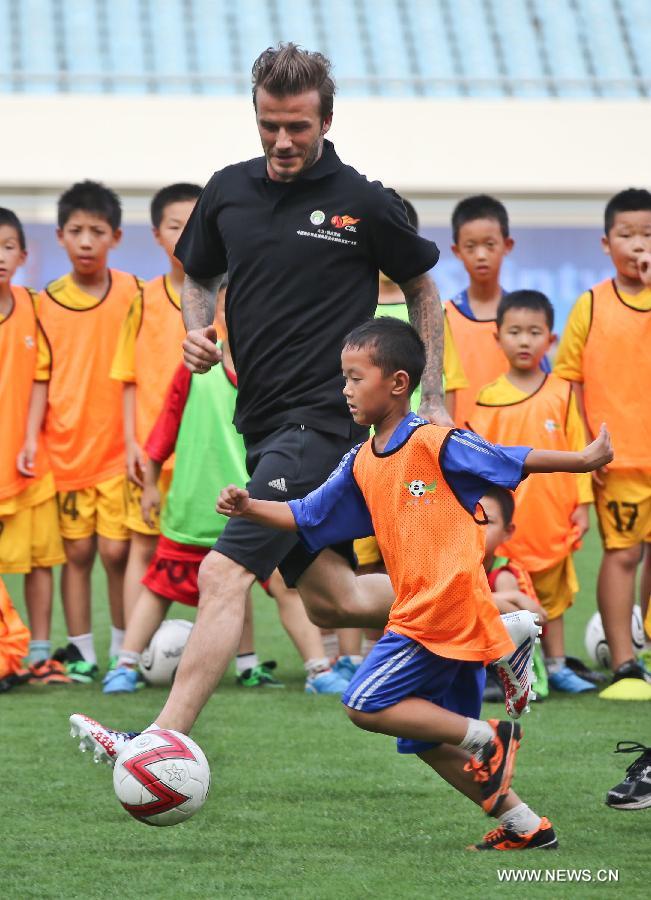 Recently retired football player David Beckham(L) takes part in a training session with students at Nanjing Olympic Center in Nanjing, east China's Jiangsu Province, June 18, 2013. Beckham is on a seven-day visit to China as the ambassador for the Football Programme in China and China's Super League. (Xinhua/Yang Lei)