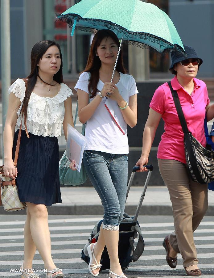 A girl holds an umbrella for shelter while walking in Shanghai, east China, June 18, 2013. The highest temperature in Shanghai reached 37 degrees centigrade on June 18. (Xinhua/Ding Ting) 