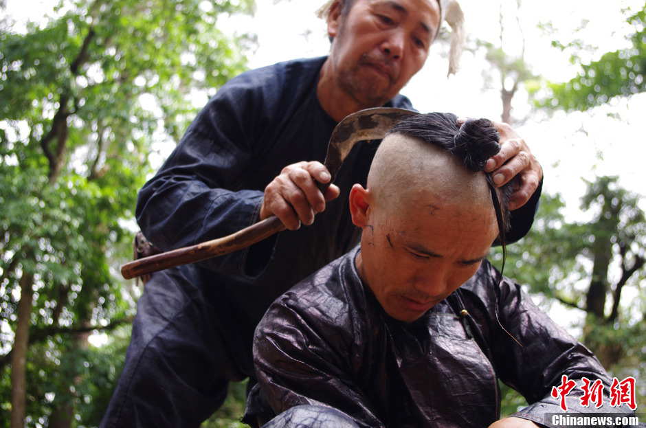 Basha people attach great importance to their hair. A man shaves his fellow’s head with a sickle. Basha men keep the hairstyle for a lifetime. (Photo by Wangchao/ Chinanews.com)