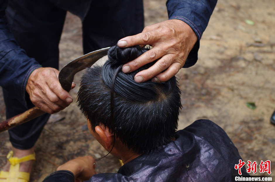 A man shaves his fellow’s head with a sickle. Basha men keep the hairstyle for a lifetime. Legend has it that the ancestors of the Basha immigrated from China's heartland to this isolated mountainous area over 2,000 years ago. (Photo by Wangchao/ Chinanews.com)