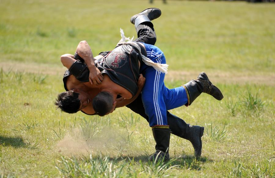 Herdsmen of the Owenke ethnic group wrestle at the annual Sebin (Happiness) Festival in Owenke Autonomous Banner, north China's Inner Mongolia Autonomous Region, June 18, 2013. The Owenke ethnic group has the reputation of the "last hunting tribe in China". (Xinhua/Liu Yongzhen)