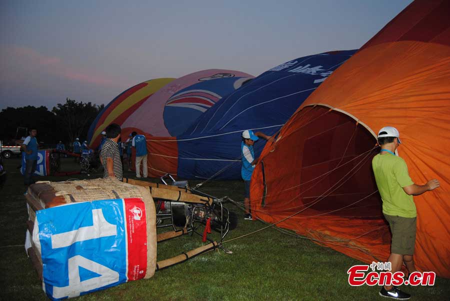 Contestants prepare for an air balloon competition in Evergreen Garden in Haikou, South China's Hainan Province, June 18, 2013. The air balloon competition kicked off on Tuesday, in which contestants are requested to fly across the Qiongzhou Strait from Haikou and reach a designated place in Xunwen County in the neighboring Guangdong Province. (CNS/Wang Xinli)