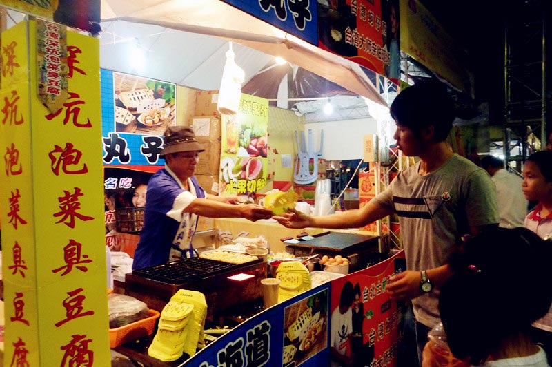 Visitors tour the Taiwan Characteristics Temple Fair in Xiamen, southeast China's Fujian Province, on Friday, June 14, 2013. The temple fair is part of the city's fifth Straits Forum to be held on June 15-21. Vendors are selling food, specialties and creative products from Taiwan at the temple fair. (CRIENGLISH.com/Yang Yong)