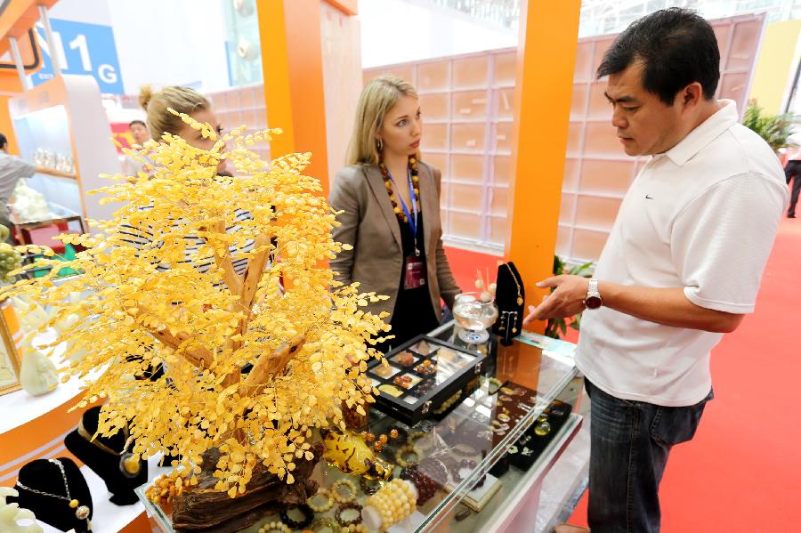 A man takes a look at the beeswax handicrafts during the 2nd China (Tianjin) International Stone Blocks, Products & Equipment Exposition in Tianjin, north China, June 18, 2013. The exposition, opened here on Tuesday, has attracted more than 800 related enterprises both at home and abroad.(Xinhua/Wang Qingyan) 