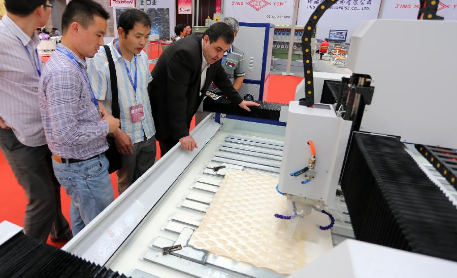 People visit a stone carving machine during the 2nd China (Tianjin) International Stone Blocks, Products & Equipment Exposition in Tianjin, north China, June 18, 2013. The exposition, opened here on Tuesday, has attracted more than 800 related enterprises both at home and abroad.(Xinhua/Wang Qingyan) 