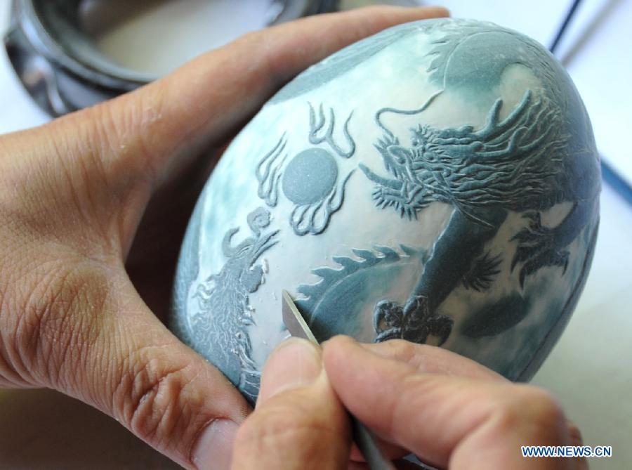 Pu Derong, a man from Dongzhuangtou Village in Zhuozhou City, makes an egg carving work in Zhuozhou, north China's Hebei Province, June 19, 2013. Pu, who started egg carving in 1995, have won several awards in various contests and exhibitions. (Xinhua/Wang Xiao)