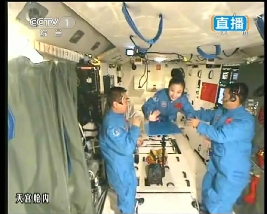 This TV grab taken on June 20, 2013 shows female astronaut Wang Yaping (C), one of the three crew members of Shenzhou-10 spacecraft, greets students on Earth aboard China's space module Tiangong-1. A special lecture began Thursday morning, given by Wang Yaping aboard China's space module Tiangong-1 to students on Earth. (Xinhua)