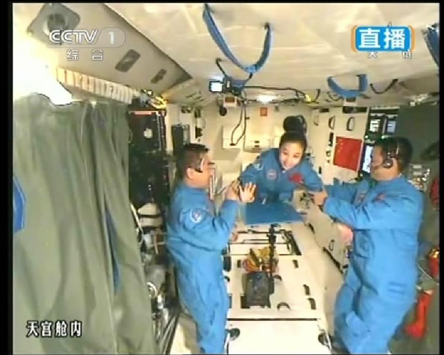 This TV grab taken on June 20, 2013 shows female astronaut Wang Yaping (C), one of the three crew members of Shenzhou-10 spacecraft, greeting students on Earth aboard China's space module Tiangong-1. A special lecture began Thursday morning, given by Wang Yaping aboard China's space module Tiangong-1 to students on Earth. (Xinhua)
