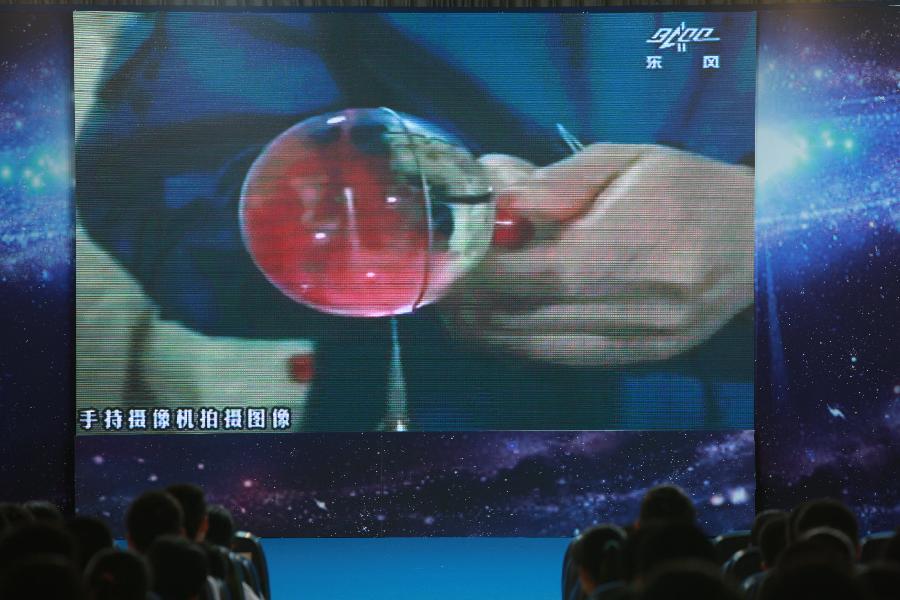 Students watch the screen showing the female astronaut Wang Yaping, one of the three crew members of Shenzhou-10 spacecraft, making a red water ball in space, at the High School Affiliated to Renmin University of China, in Beijing, capital of China, June 20, 2013. A special lecture began Thursday morning, given by Wang Yaping aboard China's space module Tiangong-1 to students on Earth. (Xinhua/Wang Yongzhuo)