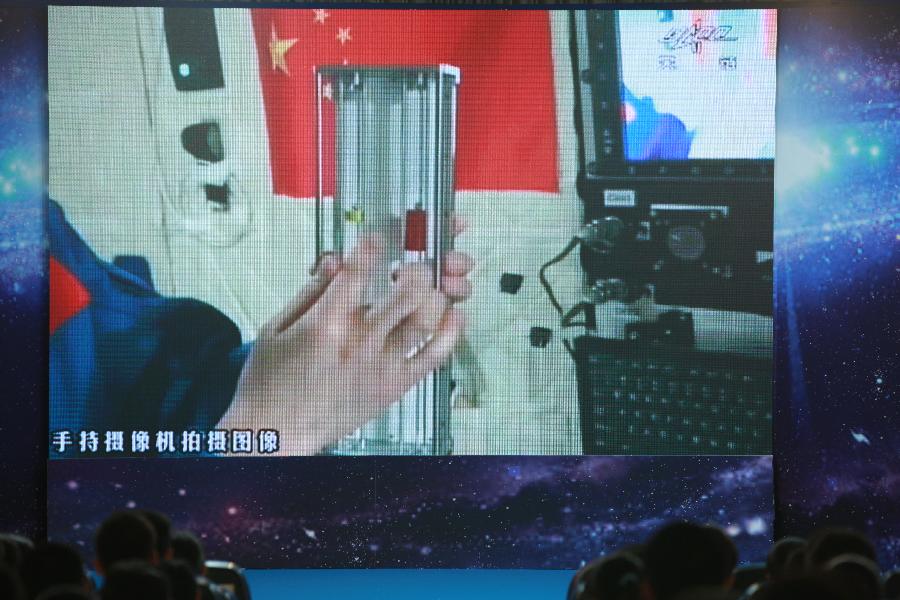 Students watch the screen showing female astronaut Wang Yaping, one of the three crew members of Shenzhou-10 spacecraft, demonstrating how to measure weight in space, at the High School Affiliated to Renmin University of China, in Beijing, capital of China, June 20, 2013. A special lecture began Thursday morning, given by Wang Yaping aboard China's space module Tiangong-1 to students on Earth. (Xinhua/Wang Yongzhuo)