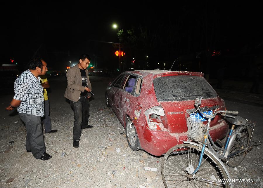 People examine a destroyed car near the locale of a restaurant blast in Shuozhou City of north China's Shanxi Province, in the early morning of June 20, 2013. Blasts ripped through a restaurant in Shuozhou Wednesday night, killing three people and injuring 149 others. (Xinhua/Yan Yan)