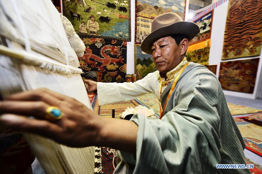 A Tibetan exhibitor knits a carpet at a Tibetan carpet exposition in Xining, capital of northwest China's Qinghai Province, June 20, 2013. Opened Thursday, the exposition attracted some 110 exhibitors from 9 countries. (Xinhua/Wu Gang) 
