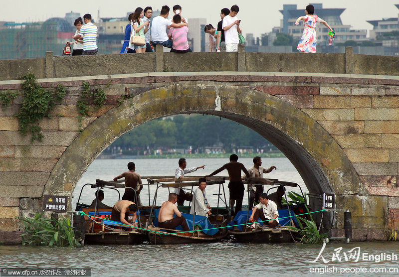 The boatmen hide in cool shade of the arch of the Broken Bridge in Hangzhou's West Lake on June 17, 2013. The temperature of the city reached 36.4 degrees Celsius on the day. (Photo/CFP)
