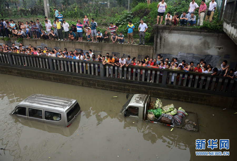 Heavy rainfall traps a van and a truck as a crowd of people observe in Chengdu, Southwest China's Sichuan province on June 20, 2013.