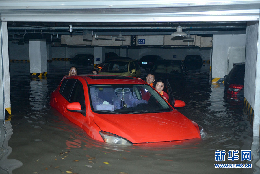 People push flooded cars out of a garage in Chengdu, Southwest China's Sichuan province on June 20, 2013.