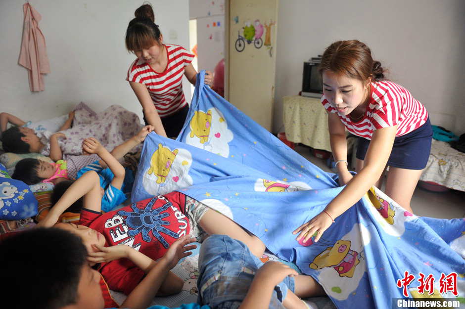 Volunteers tuck children with autism into bed to have a nap after lunch. It has been 5 years since Li established the non-profit classroom specifically for children with autism in Taiyuan, north China’s Shanxi province. (Photo by Weiliang/ Chinanews.com)