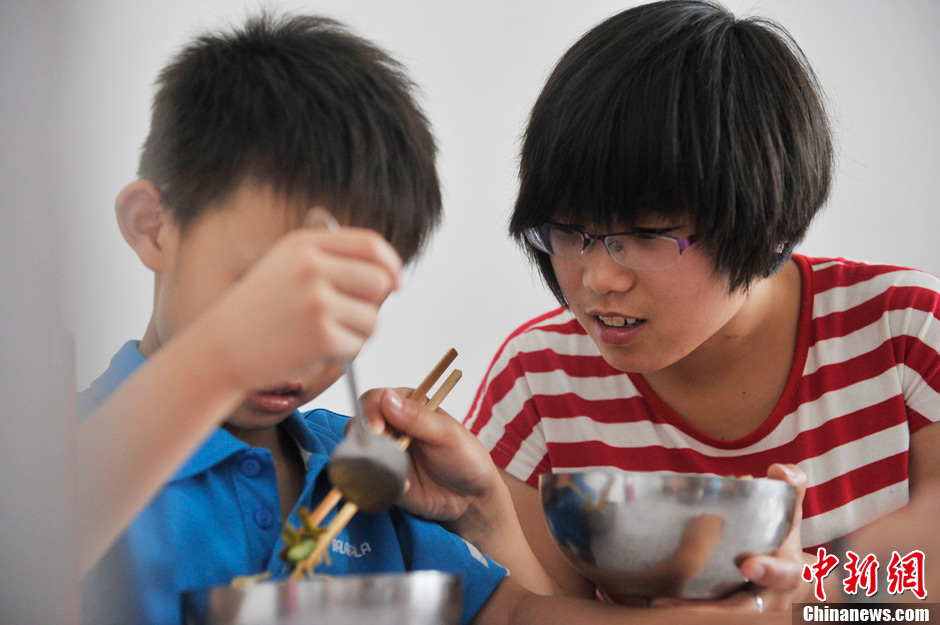 A volunteer helps a child with autism have lunch. It has been 5 years since Li established the non-profit classroom specifically for children with autism in Taiyuan, north China’s Shanxi province.  (Photo by Weiliang/ Chinanews.com)