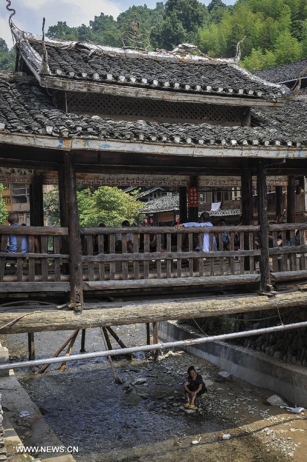 People rest at a wind and rain bridge of Zhaoxing Dong Village in Liping County, southwest China's Guizhou Province, June 20, 2013. Zhaoxing Dong Village is one of the largest Dong village in Guizhou. In 2005, it was ranked one of China's six most beautiful villages and towns by Chinese National Geography. (Xinhua/Ou Dongxu) 