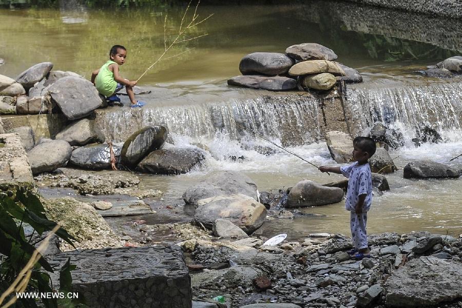 Children play near a brook at Zhaoxing Dong Village in Liping County, southwest China's Guizhou Province, June 20, 2013. Zhaoxing Dong Village is one of the largest Dong village in Guizhou. In 2005, it was ranked one of China's six most beautiful villages and towns by Chinese National Geography. (Xinhua/Ou Dongxu)