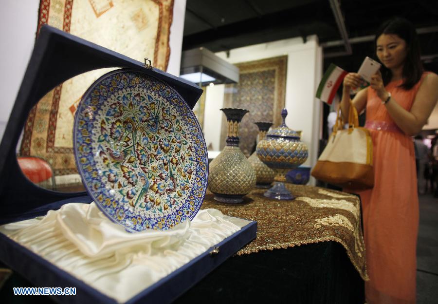 A woman takes a photo of the displayed Iranian handicrafts during the Iran Cultural Week in Beijing, capital of China, June 20, 2013. The seven-day cultural week opened here Thursday. (Xinhua/Wang Shen) 