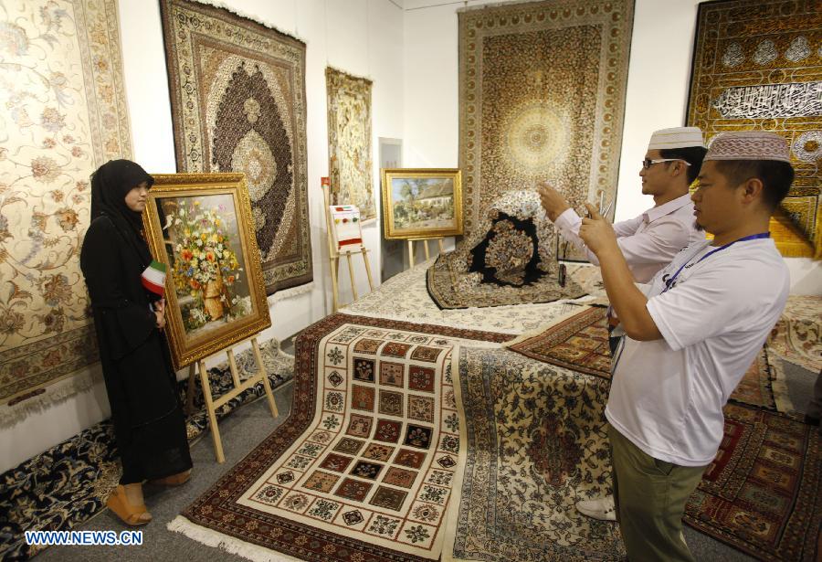 A visitor poses for a photo before the displayed Iranian handicrafts during the Iran Cultural Week in Beijing, capital of China, June 20, 2013. The seven-day cultural week opened here Thursday. (Xinhua/Wang Shen) 