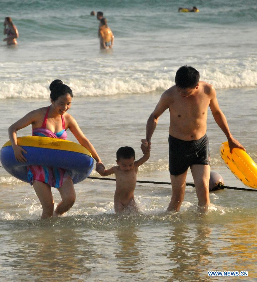A family play at Dadonghai in Sanya, south China's Hainan Province, June 20, 2013. People took actions to keep away from heat as the temperature in Sanya reached 30 degrees centigrade above recently. (Xinhua/Zhang Yongfeng)