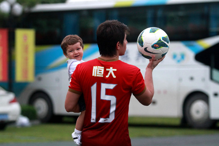 Successfully mugging for the camera: A warm-up match on June 15, 2013: Guangzhou Evergrande vs Shenzhen Ruby, Conca plays with his boy on the sidelines. (Photo/Osports)