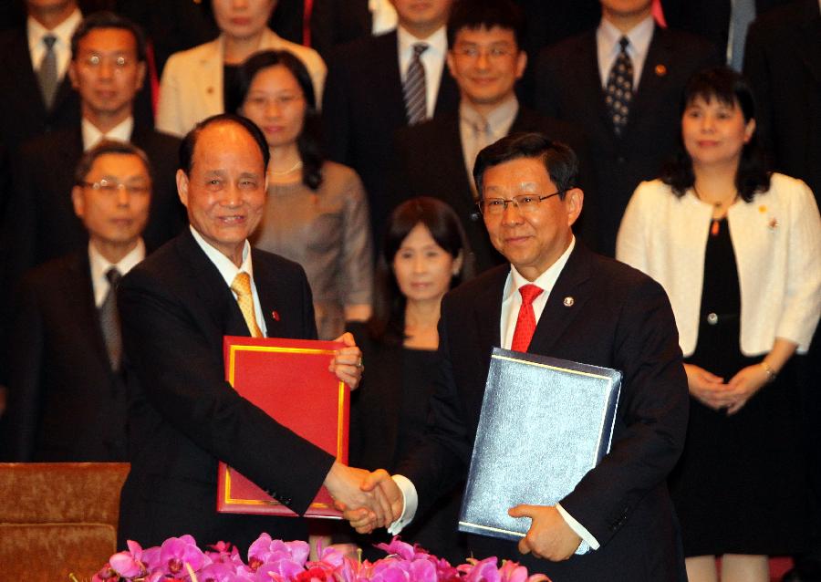 Lin Join-sane (L), chairman of the Taiwan-based Straits Exchange Foundation (SEF), shakes hands with Chen Deming, president of the mainland-based Association for Relations Across the Taiwan Straits (ARATS), during the signing ceremony of a cross-Strait service trade agreement in Shanghai, east China, June 21, 2013. (Xinhua/Ren Long) 