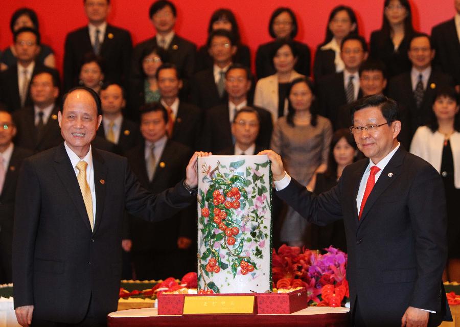 Lin Join-sane (L), chairman of the Taiwan-based Straits Exchange Foundation (SEF), presents a coloured glaze artwork to Chen Deming (R), president of the mainland-based Association for Relations Across the Taiwan Straits (ARATS), during the signing ceremony of a cross-Strait service trade agreement in Shanghai, east China, June 21, 2013. (Xinhua/Ren Long) 