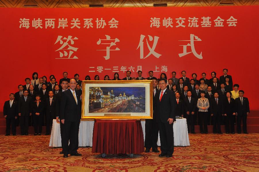 Chen Deming (R, front), president of the mainland-based Association for Relations Across the Taiwan Straits (ARATS), presents a gift to Lin Join-sane (L, front), chairman of the Taiwan-based Straits Exchange Foundation (SEF), during the signing ceremony of a cross-Strait service trade agreement in Shanghai, east China, June 21, 2013. (Xinhua/Chen Yehua)