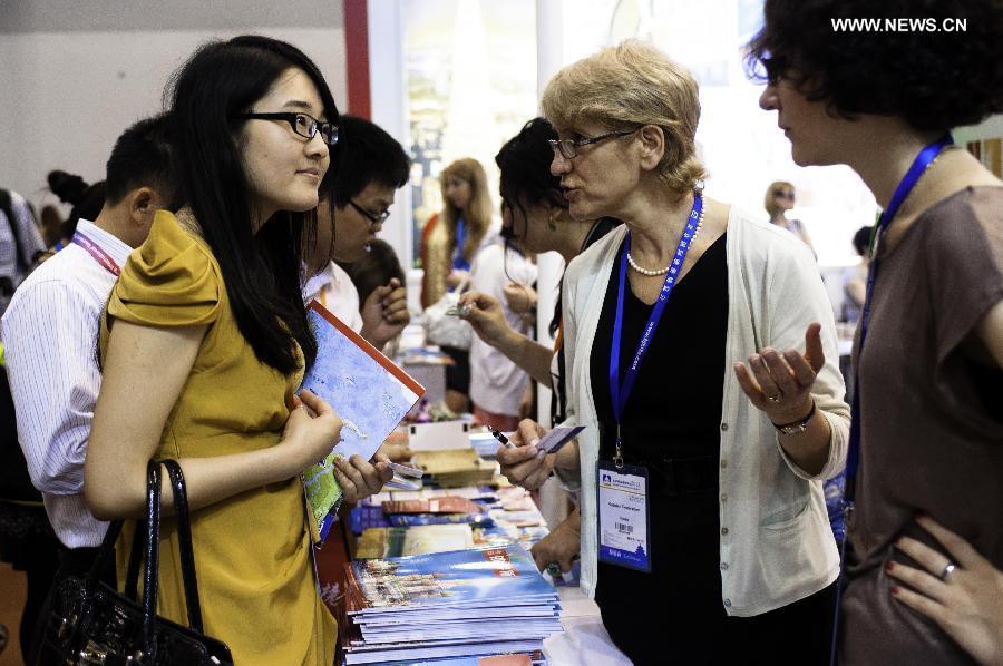 A visitor talks with a Russian exhibitor at the Beijing International Tourism Expo (BITE) 2013 in Beijing, capital of China, June 21, 2013. The BITE 2013 kicked off on Friday, attracting 887 exhibitors from 81 countries and regions. (Xinhua/Liu Jinhai) 