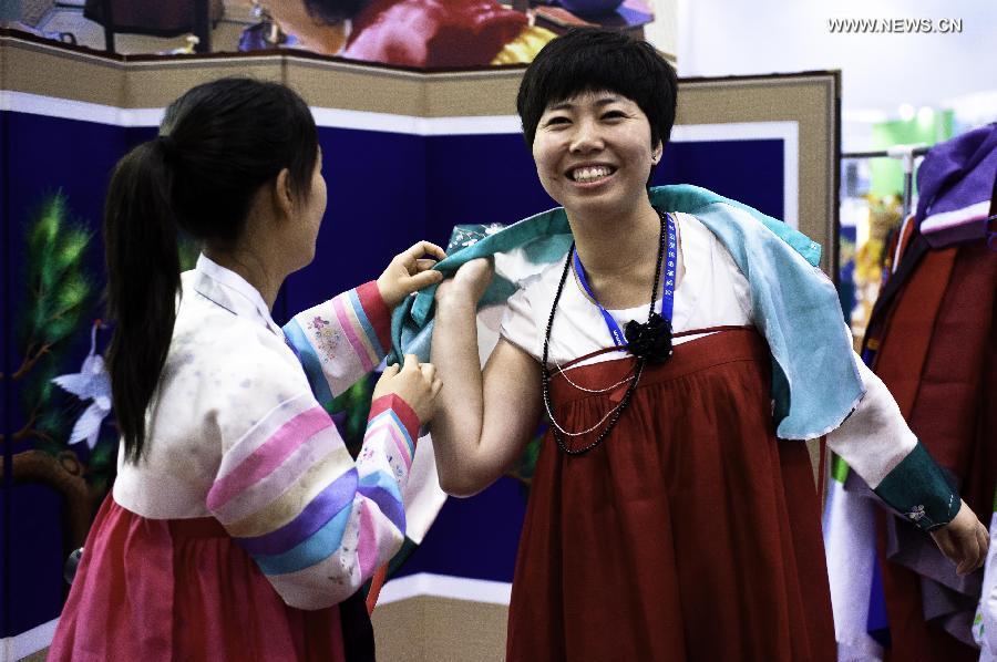 A visitor tries on traditional Korean costume at the Beijing International Tourism Expo (BITE) 2013 in Beijing, capital of China, June 21, 2013. The BITE 2013 kicked off on Friday, attracting 887 exhibitors from 81 countries and regions. (Xinhua/Liu Jinhai) 