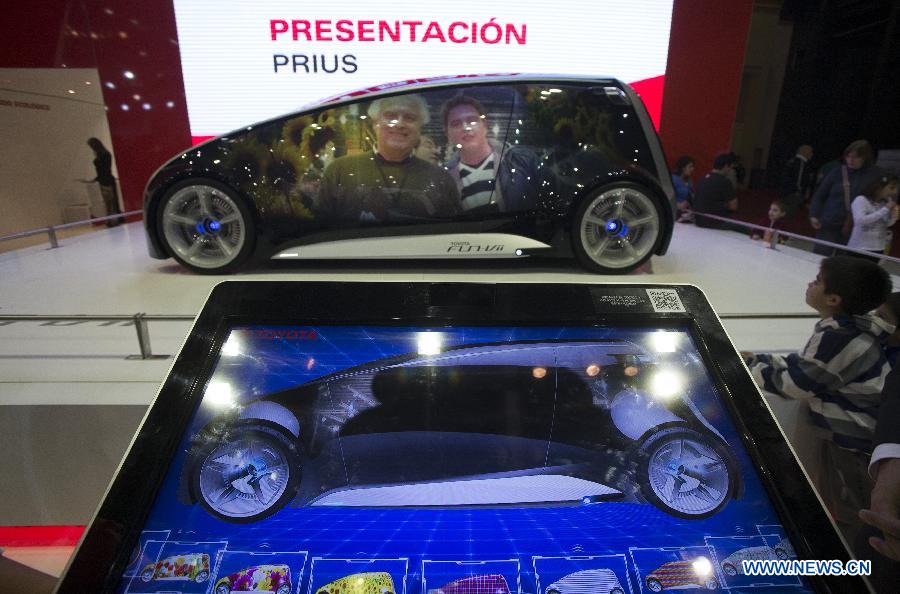 People reflect themselves on the bodywork of a Toyota's Fun Vii concept car during the 6th International Auto Show, in the city of Buenos Aires, capital of Argentina, on June 21, 2013. (Xinhua/Martin Zabala)
