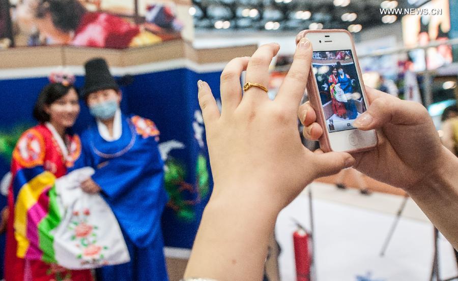 Visitors wearing traditional Korean costumes pose for photo at the Beijing International Tourism Expo (BITE) 2013 in Beijing, capital of China, June 21, 2013. The BITE 2013 kicked off on Friday, attracting 887 exhibitors from 81 countries and regions. [Photo: Xinhua/Zhang Yu] 