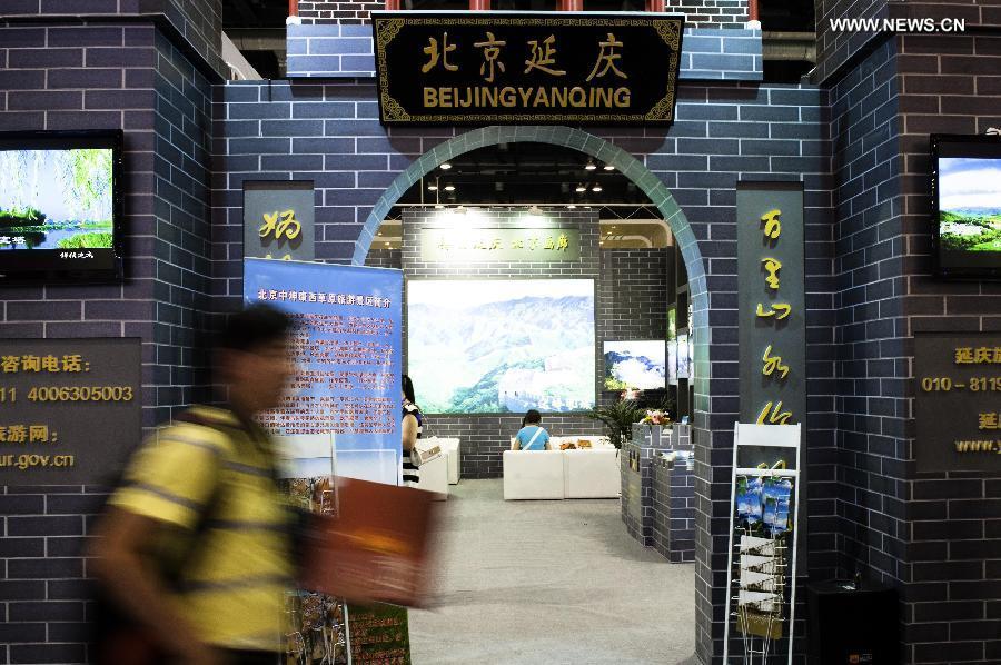 A visitor walks past the exhibition area of Beijing's Yanqing County at the Beijing International Tourism Expo (BITE) 2013 in Beijing, capital of China, June 21, 2013. The BITE 2013 kicked off on Friday, attracting 887 exhibitors from 81 countries and regions. [Photo: Xinhua/Liu Jinhai] 