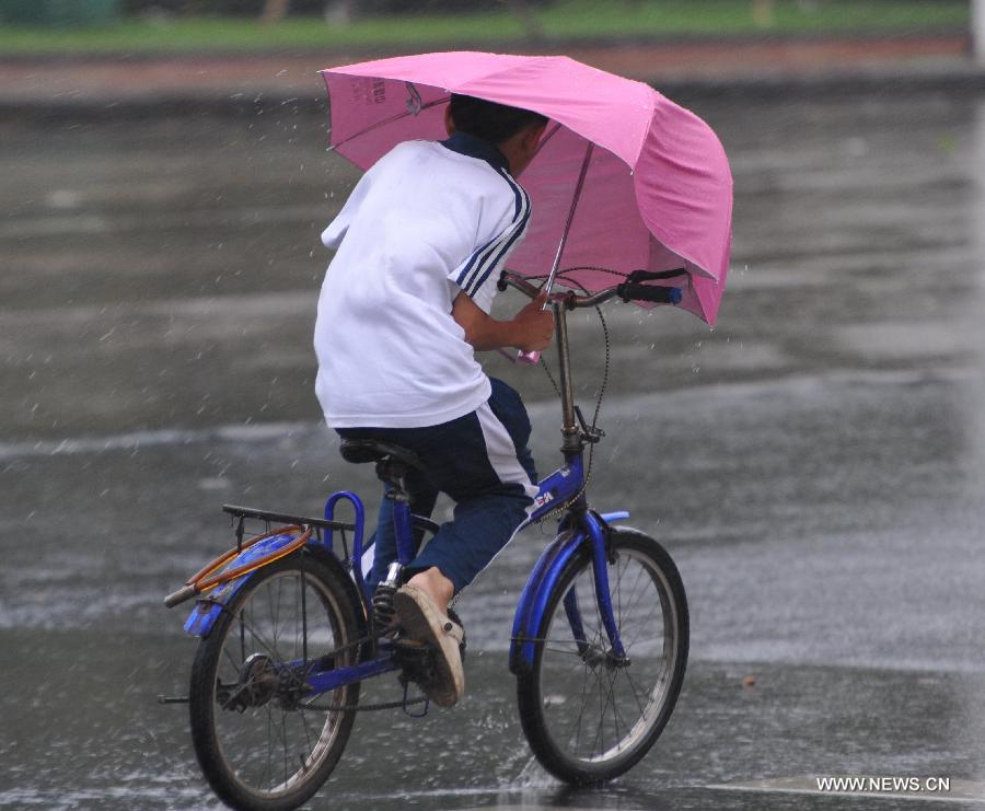 A boy rides in the rain in Qionghai City, south China's Hainan Province, June 22, 2013. Tropical storm "Bebinca" is estimated to arrive in south China's Guangdong Province on Saturday afternoon, the first to make landfall in China this year, the National Meteorological Center (NMC) said on Saturday. Affected by the tropical storm, coastal areas in Hainan and Guangdong provinces were battered by gales and torrential rain, the center reported. (Xinhua/Meng Zhongde) 