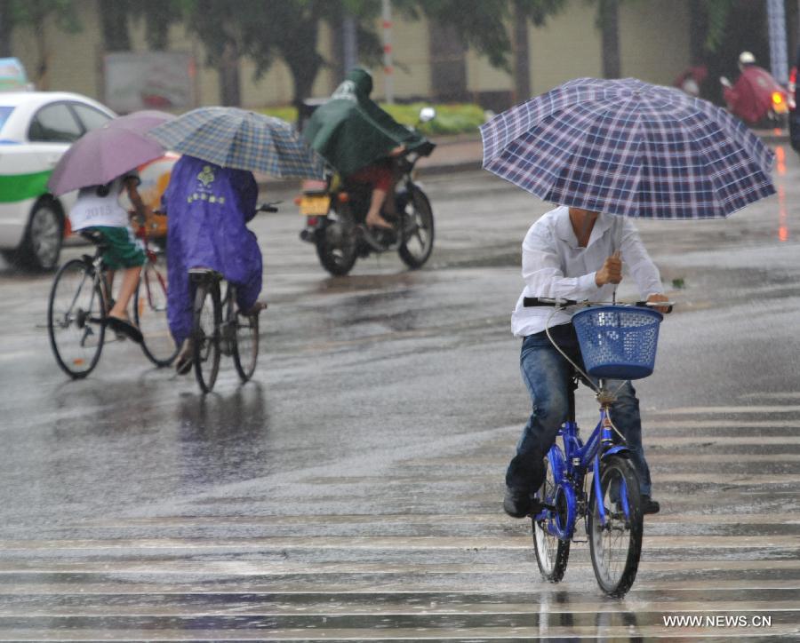 People ride in the rain in Qionghai City, south China's Hainan Province, June 22, 2013. Tropical storm "Bebinca" is estimated to arrive in south China's Guangdong Province on Saturday afternoon, the first to make landfall in China this year, the National Meteorological Center (NMC) said on Saturday. Affected by the tropical storm, coastal areas in Hainan and Guangdong provinces were battered by gales and torrential rain, the center reported. (Xinhua/Meng Zhongde) 