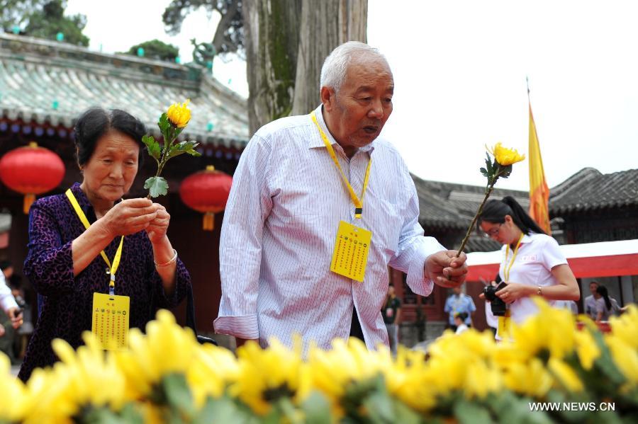 People present flowers during a sacrifice ceremony at "the Temple of Fu Xi" in Tianshui, northwest China's Gansu Province, June 22, 2013. More than 20,000 Chinese from China and abroad attended a sacrifice ceremony held here Saturday to pay tribute to Fu Xi, a culture hero who is believed to be the inventor of writing, fishing and hunting. Fu Xi is regarded as one of the ancestors of the Chinese nation. (Xinhua/Chen Bin) 