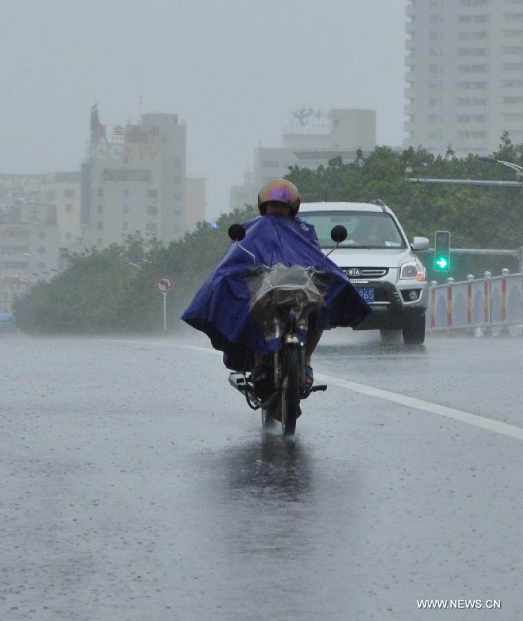 People ride in the rain in Sanya City, south China's Hainan Province, June 22, 2013. Tropical storm "Bebinca" made landfall in Tanmen Township in Hainan's city of Qionghai at 11:10 a.m., the local meteorological department said. Train and shipping services across the Qiongzhou Strait have been suspended due to the arrival of Bebinca. (Xinhua/Wang Junfeng) 