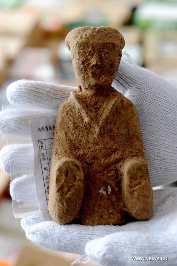 An archaeologist displays a unearthed terracotta figurine at Guxiang Township in Linying County, central China's Henan Province, June 22, 2013. Chinese archaeologists have discovered a well-reserved large burial complex dating back to the Warring States Period (475-221 BC) and the West Han (206 B.C.--25 AD.) Dynasty along the local section of the south-to-north water diversion project recently. Some 412 cultural relics have been unearthed in 119 excavated tombs. (Xinhua/Zhu Xiang)