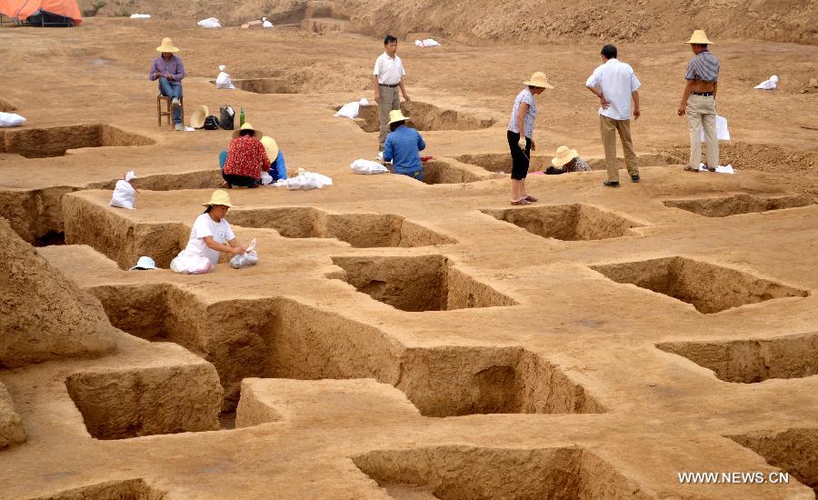 In this photo taken on June 8, 2013, archaeologists work at an ancient burial complex at Guxiang Township in Linying County, central China's Henan Province. Chinese archaeologists have discovered a well-reserved large burial complex dating back to the Warring States Period (475-221 BC) and the West Han (206 B.C.--25 AD.) Dynasty along the local section of the south-to-north water diversion project recently. Some 412 cultural relics have been unearthed in 119 excavated tombs. (Xinhua/Zhu Xiang) 
