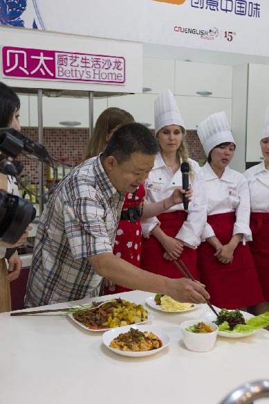 Kiting Steven from Australia gets advice from the judge during the Chopsticks & Beyond Chinese Cooking Challenge on June 22, 2013. "Chopsticks and Beyond" is a Chinese cuisine challenge launched by CRIENGLISH.com to provide a platform for foreign food enthusiasts to show off their Chinese cooking skills and explore creative dishes with exotic flavor. It features China's four great traditions: Sichuan Cuisine, Cantonese Cuisine, Shandong Cuisine and Huaiyang Cuisine.(Xinhuanet/Yang Yi)