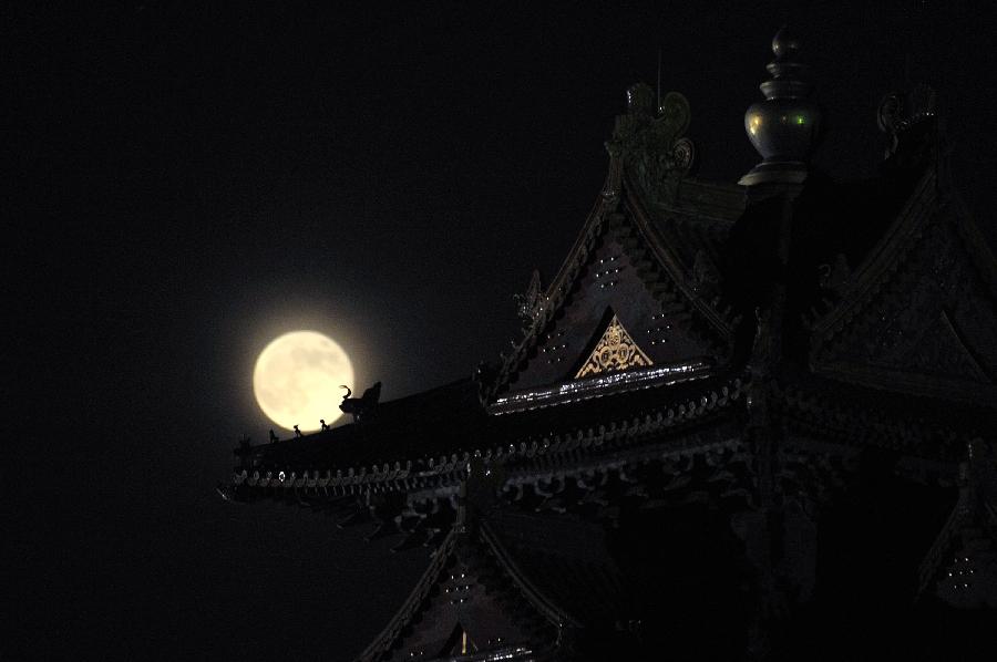 A full moon sets behind a building of the Forbidden City in Beijing, capital of China, June 23, 2013. The moon looks 14 percent larger and 30 percent brighter than usual on Sunday. The scientific term for the phenomenon is "perigee moon", but it is also known as a "super moon". (Xinhua/Sun Ruibo) 