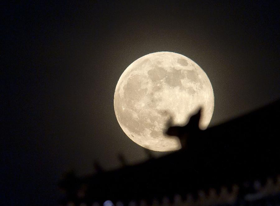 A full moon sets behind a building of the Forbidden City in Beijing, capital of China, June 23, 2013. The moon looks 14 percent larger and 30 percent brighter than usual on Sunday. The scientific term for the phenomenon is "perigee moon", but it is also known as a "super moon". (Xinhua/Chen Duo) 