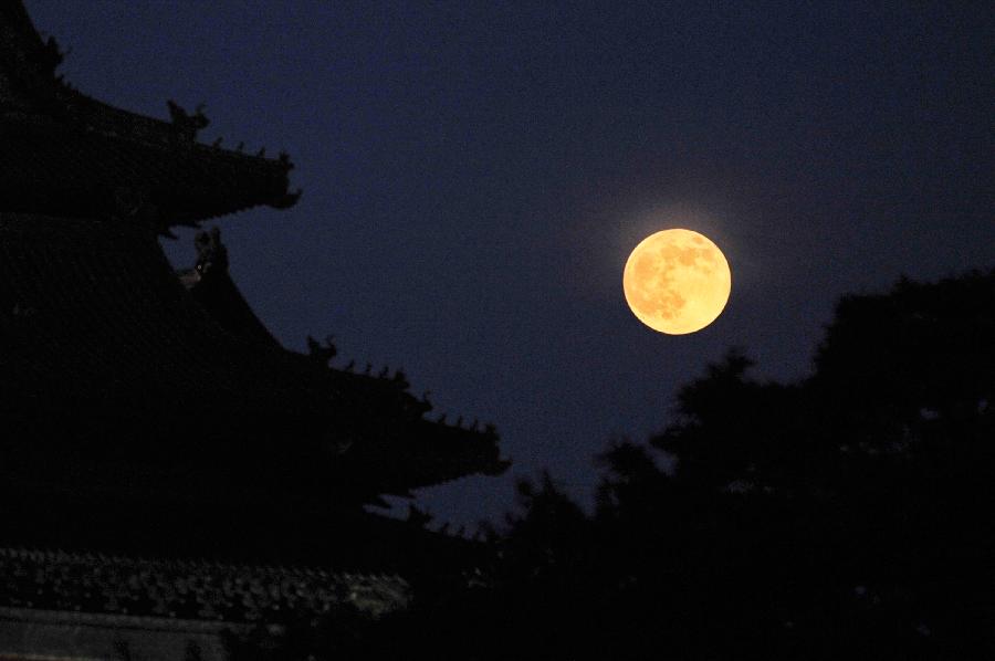 A full moon sets behind a building of the Forbidden City in Beijing, capital of China, June 23, 2013. The moon looks 14 percent larger and 30 percent brighter than usual on Sunday. The scientific term for the phenomenon is "perigee moon", but it is also known as a "super moon". (Xinhua/Sun Ruibo) 