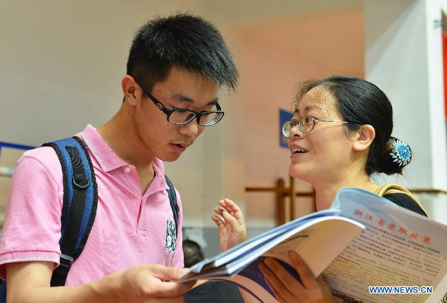 A student and his mother are seen at a college enrollment consultation fair in Hangzhou, capital of east China's Zhejiang Province, June 23, 2013. The fair attracted representatives of nearly 200 colleges. Approximately 9.12 million people all over China took part in the National College Entrance Examination early June. (Xinhua/Li Zhong)