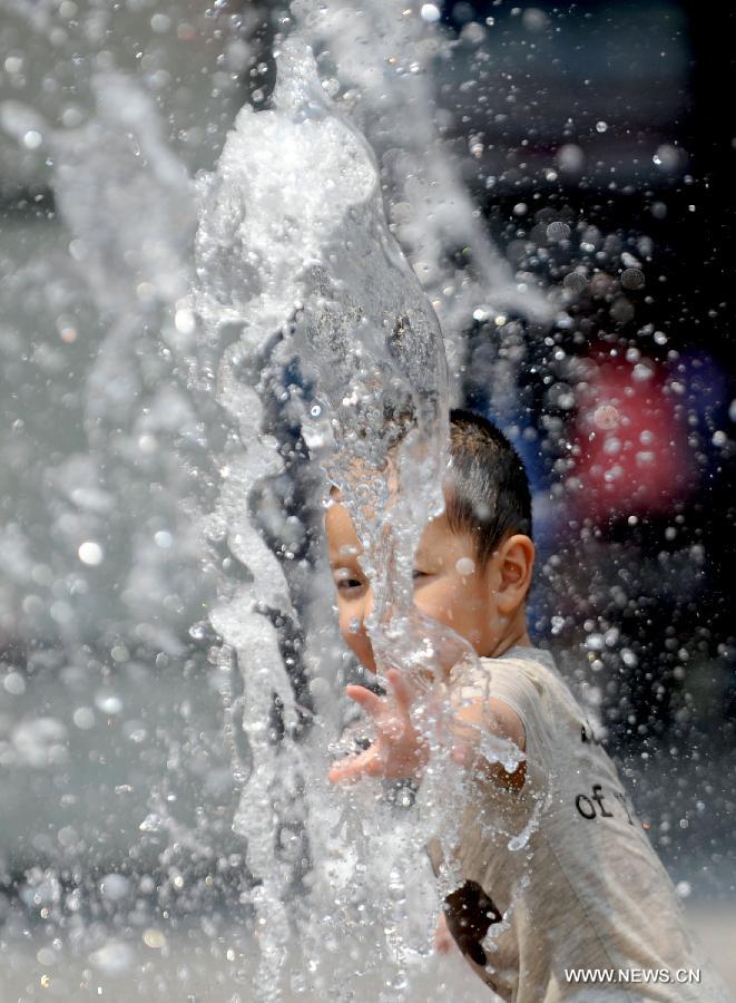 A child frolics at a fountain in Shenyang, capital of northeast China's Liaoning Province, June 23, 2013. (Xinhua/Zhang Wenkui)