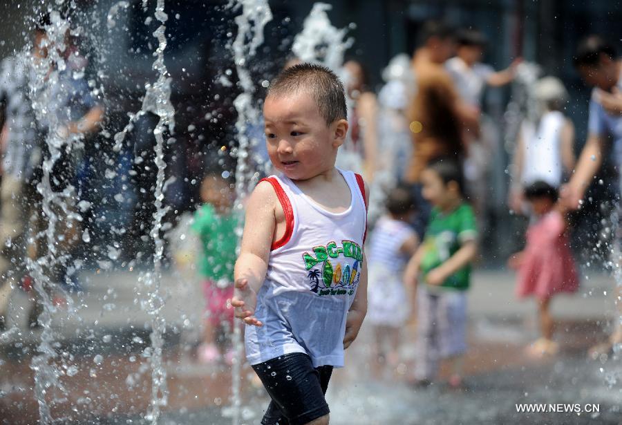 A child frolics at a fountain in Shenyang, capital of northeast China's Liaoning Province, June 23, 2013. (Xinhua/Zhang Wenkui)