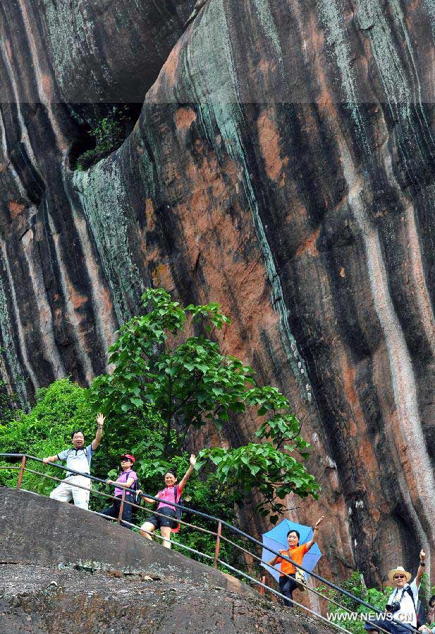 Tourists wave while visiting Mountain Danxiashan, in Shaoguan City, south China's Guangdong Province, on June 22, 2013. Mountain Danxiashan entered a peak tourist season recently with the coming of summer. (Xinhua/Chen Haining)
